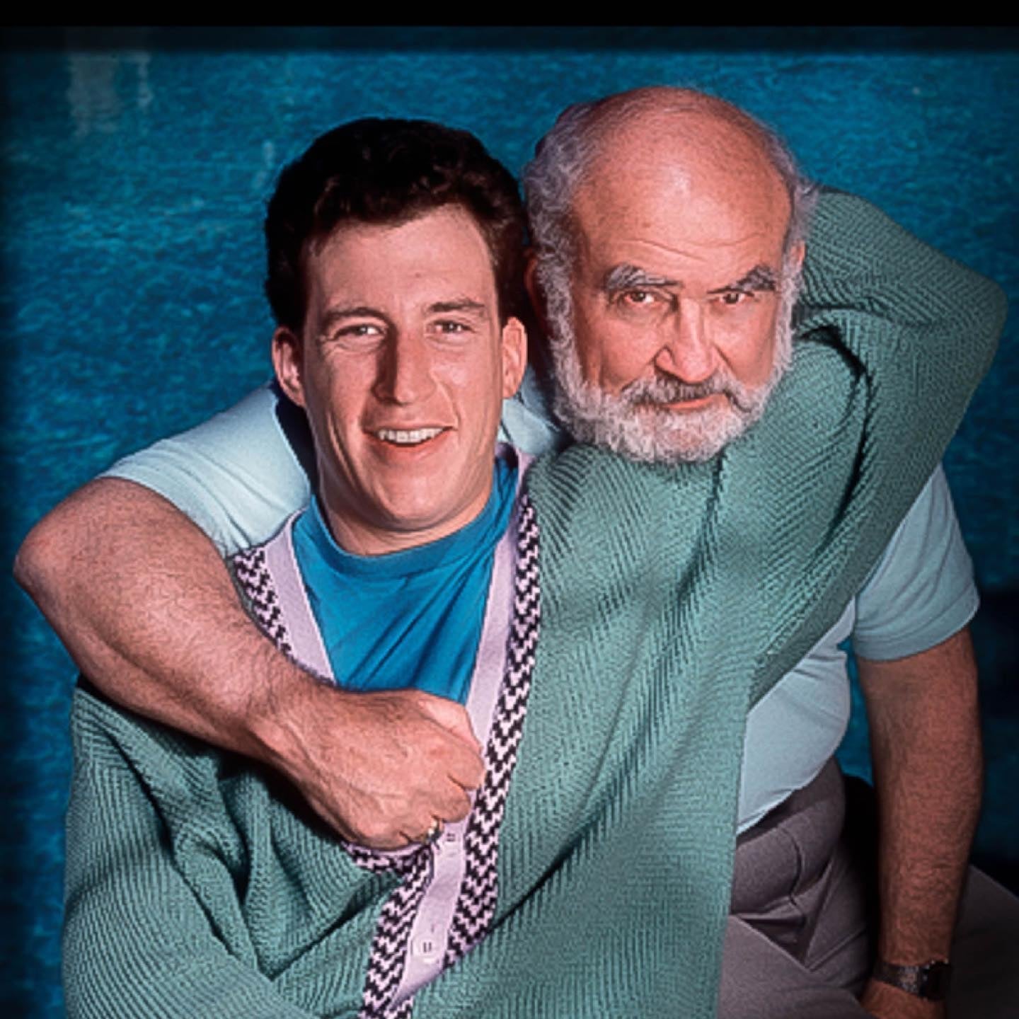 Matthew Asner in a blue-green posing with his father in a light blue t-shirt.